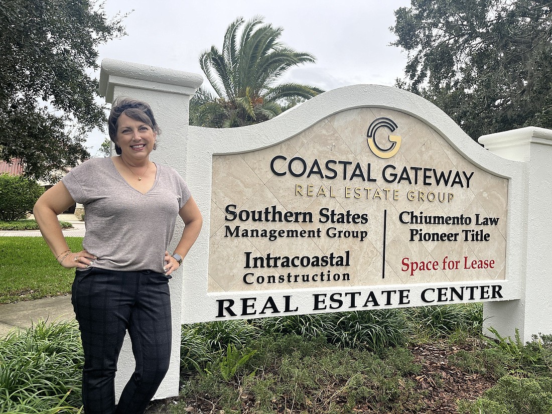 Intracoastal Construction Director of Sales Alesha Richmond stands by the sign at the Coastal Gateway building. Courtesy photo